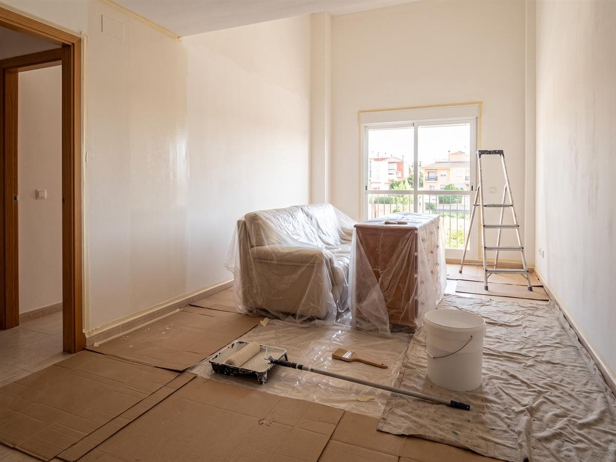 Salón de una vivienda con los muebles y el suelo protegidos durante los trabajos de pintura de AZL en A Coruña